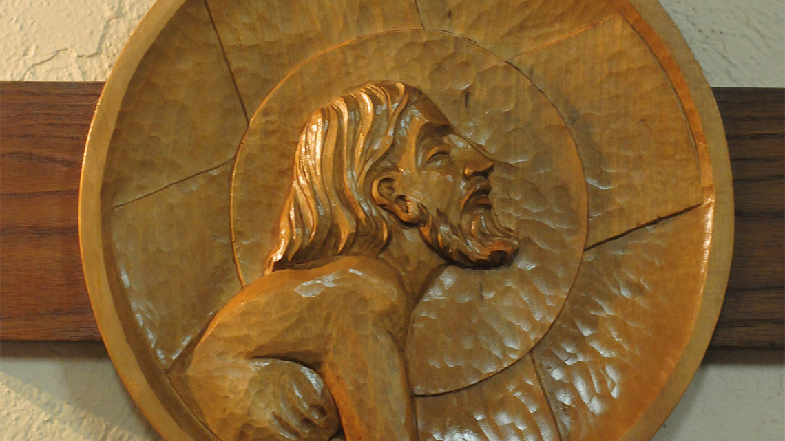Christ depicted at one of the Stations of the Cross. Each station is a circular relief carving in wood.